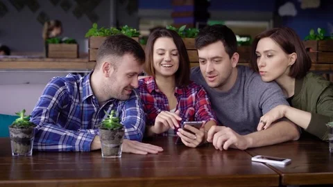 Friends watching smart phone while sitting in restaurant Stock-Footage 75522817