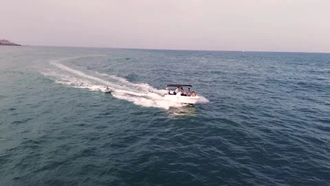 Friends water skiing over inflatable donut pulled by boat Stock Footage 246791753