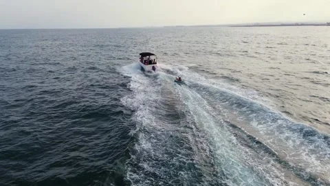 Friends water skiing over inflatable donut pulled by boat Stock Footage 246791817