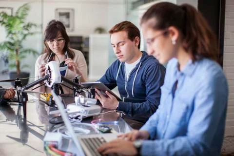 Friends working with electrical equipment at table in classroom Stock Photos
