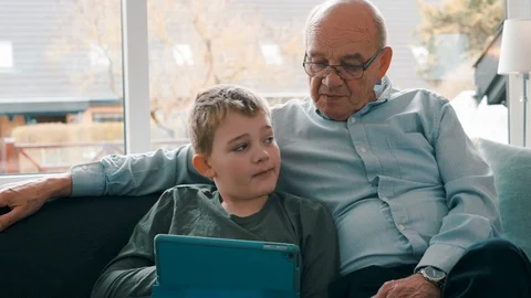Friendship between two generations as boy and senior man watch content on tablet Video stock 105129641