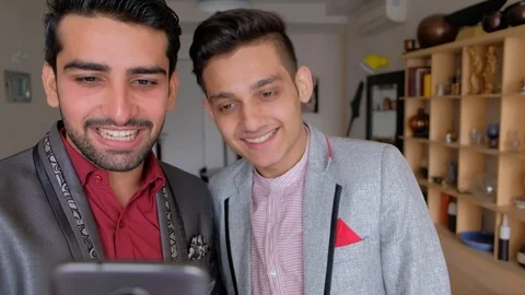 Friendship between two young males as they share something on their smart phone  Stock Footage 101290730