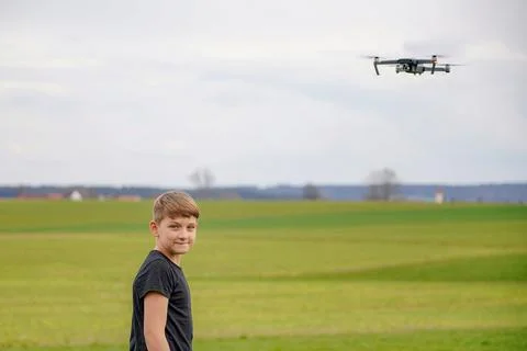 A frightened boy got stressed when he saw a quadcopter in the field. 库存照片