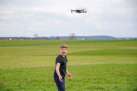 A frightened boy got stressed when he saw a quadcopter in the field. Stock Photos
