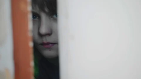 A frightened boy peeks through a crack in the door. Interesting look Видео 130049020