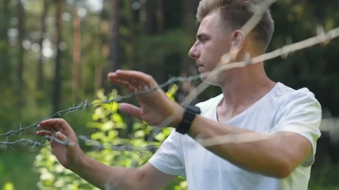 Frightened caucasian guy running through the forest, bumped into a barbed wire Stock Footage 157072594