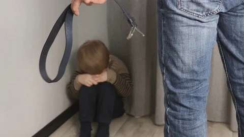 A frightened, crying child is sitting in the corner of the room. Violence Stock Footage 125999928
