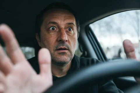 Frightened driver reacting suddenly inside car, shocked expression and rais.. Stock Photos