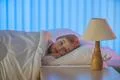 The frightened girl lay on the bed. Evening night time Photo