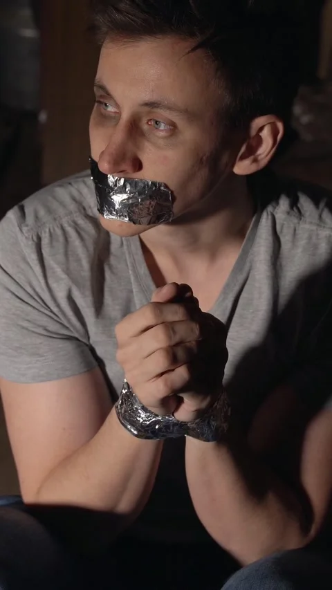 Frightened kidnapping victim with a bruised eye, bound wrists and taped mouth Stock Footage 345406455