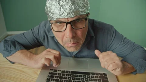 A Frightened Man in a Foil Cap Sitting at a Laptop, Anxiously Looking Around. Stock Footage 166650642
