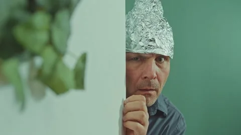 A Frightened Man in a Protective Foil Cap Peeking Strangely Around the Corner 動画素材 166706633