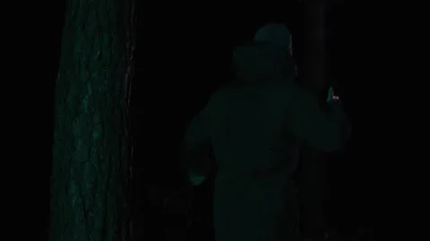 A frightened man runs through a dark forest at night, lighting his way with a Video stock 302888899
