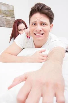 Frightened man trying to escape from the bed because woman Stock Photos
