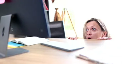 Frightened woman looking at computer screen from under table 4k movie slow Stock Footage 219949797