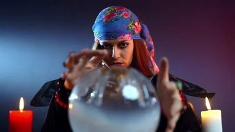 Frightful witch using round crystal ball for spelling over it, gypsy sitting in Stock-Footage 143725056