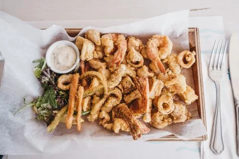 Frito misto fried seafood on a wooden tray in a restaurant. Stock Photos
