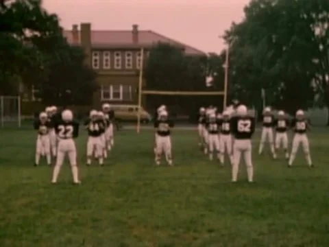Front and side view of high school football team preparing for game, 1980s Stock Footage 61766861