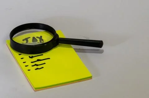In front of the block, there is a yellow notepad with the word "TAX" writte.. Stock Photos
