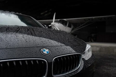 The front of a bmw car with a plane in the background Stock Photos