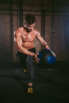 In front of the camera athletic guy details using a cross fit ball doing hard Stock Photos