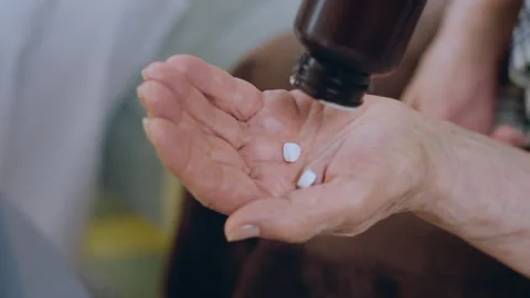 In front of the camera capturing video of a old hand holding two medical pills Stock Footage 255114981