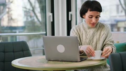 In front of the camera at coffee shop pretty lady take her coffee and working on Stock Footage 170489917