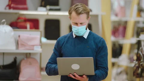 In front of the camera handsome salesman with a protective mask working in the Stock Footage 169866418