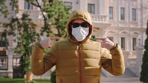 In front of the camera with a protective mask on face a guy suggesting to Stock Photos