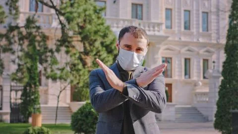 In front of the camera with a protective mask on face a guy suggesting to Stock Photos