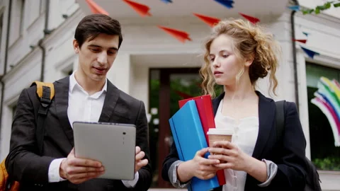 In front of the camera walking two students analyzing something after they Stock Footage 146391651