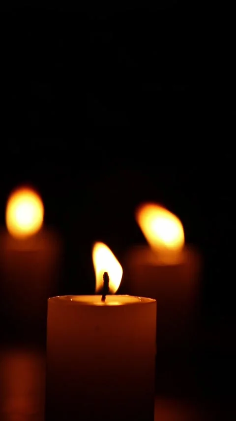 Front candle flame with two blurred candles glowing in background Stock Footage 323674321