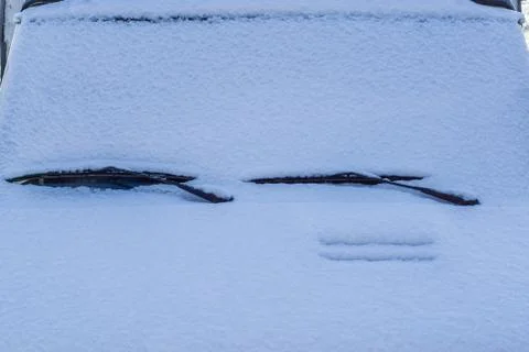 The front of a car fully covered in white snow, only showing the window wiper Stock Photos