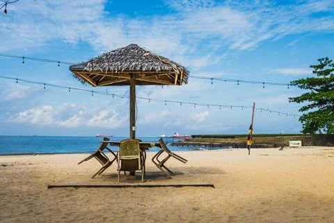 Front centered view of a tropical hut with a thatched roof umbrella and out.. Stock Photos