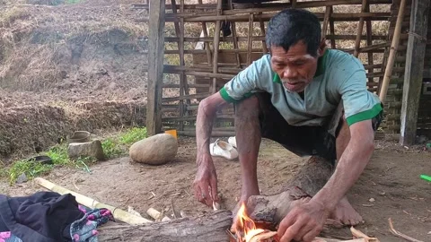 Front close-up of an elderly Indonesian farmer tending a cooking. Stock Footage 321933491