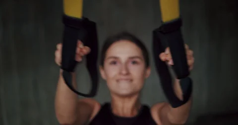 Front close up portrait of pleasant young woman training using TRX holding loops Stock Footage 123662276