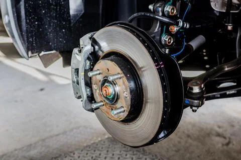 Front disc brake on car in process of new tire replacement. The rim is remove Stock Photos