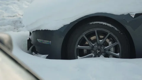 Front end and wheel of Tesla electric car covered in snow. Stock Footage 329224590
