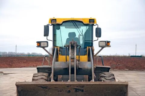 Front-end loader at a construction site. Big loader close-up. Stock Photos