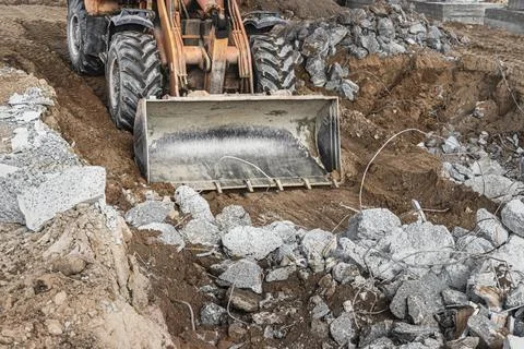 A front-end loader at a construction site removes debris from reinforced Photos