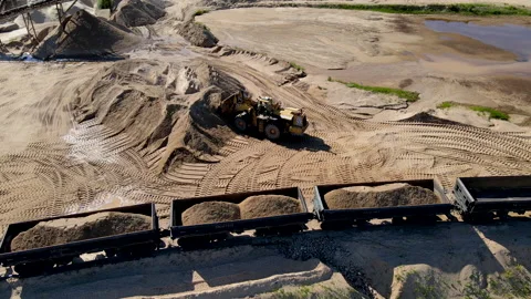 Front-end loader loading sand it to the freight train. Видео 156621112