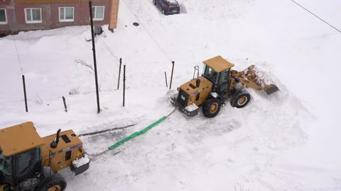 Front End Loader towing and pulls out another Wheel Loader, which is deeply Stock Footage 327627906