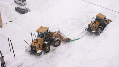 Front End Wheel Loader towing, pulling out another Front End Loader that is Stock Footage 327627699