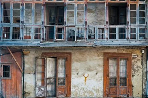 Front facade with windows and a closed terrace of an old and abandoned house. Stock Photos