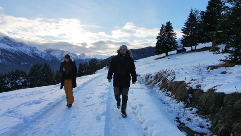 Front facing drone shot of a couple walking through a snowy alpine landscape Stock Footage 324555915