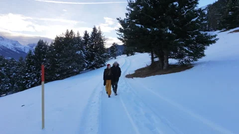Front facing drone wide shot of a couple walking through a snowy alpine land Stock Footage 324556059