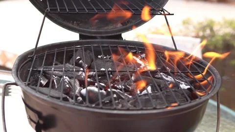Front-facing shot of a charcoal BBQ grill with open flames and glowing coals Stock Footage 337891933