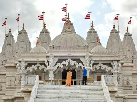 Front-facing view of an ornate white marble Hindu temple with carved domes and Stock Photos