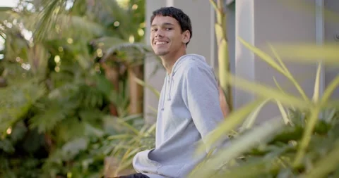 Front foliage blurring, African-American man in gray hoodie sitting on bench, Stock Footage 339679058
