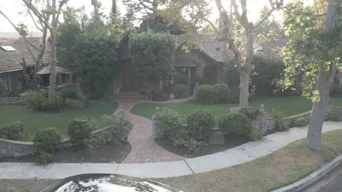 Front garden and brick path of a stone cottage on a quiet street Stock Footage 345546304